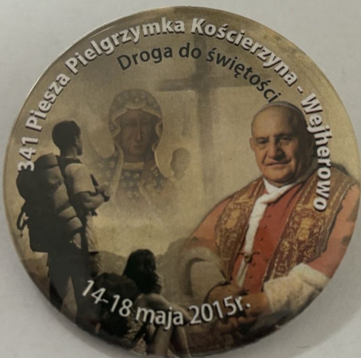 Okrągłą plakietka w brązowych barwach z pielgrzymki do Wejherowa. Na plakietce wizerunek świętego, obraz Matki Boskiej i wędrowiec.