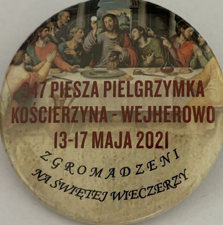 Okrągła plakietka w jasnobrązowych kolorach z 347 pielgrzymki z Kościerzyny do Wejherowa. Na plakietce obraz ostatniej wieczerzy.
