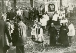 Pielgrzymka z Gdańska-Oliwy na Kalwarię Wejherowską. Grupa pielgrzymów. Widać siostry zakonne, obraźniczki i obraźników z feretronem. Zdjęcie czarno-białe.
